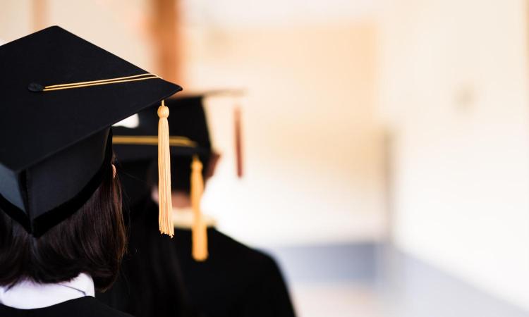 A couple of students wearing caps with their backs to the camera.