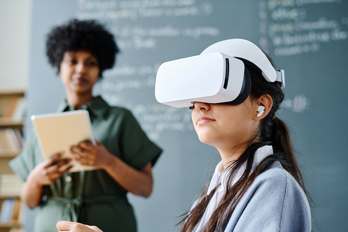 A teacher takes notes while watching a student using VR glasses.