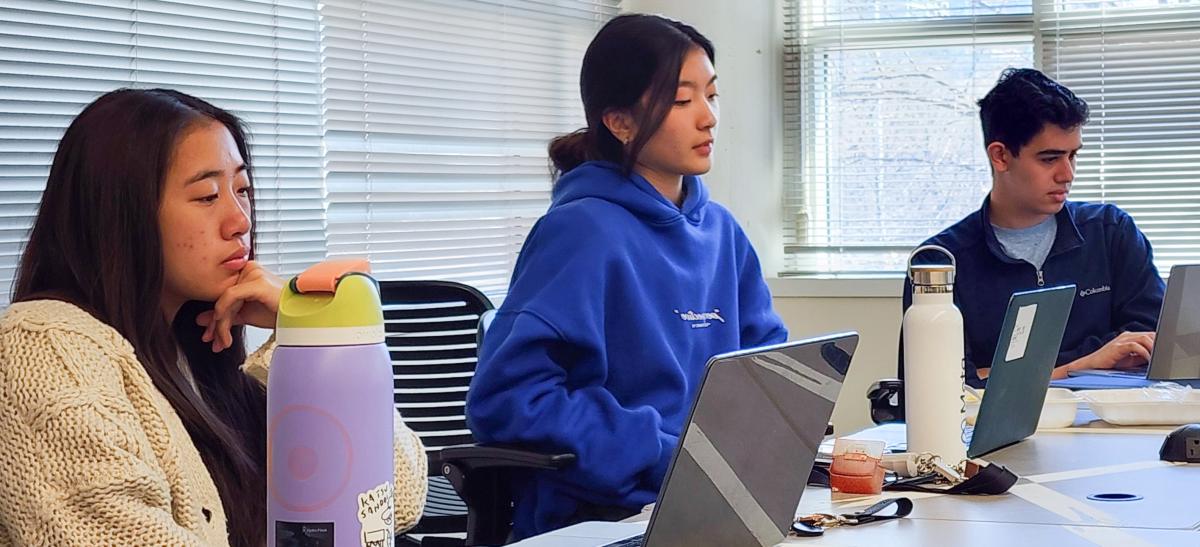 VIP C21U 2023 students, two Asian females and one Caucasian male looking at their computers.