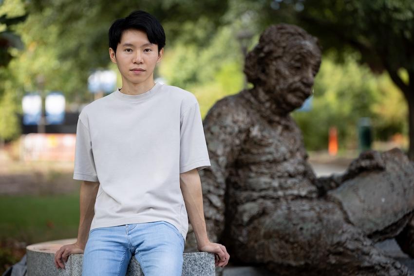 Ray Hung sitting in front of Georgia Tech's Einstein sculpture.