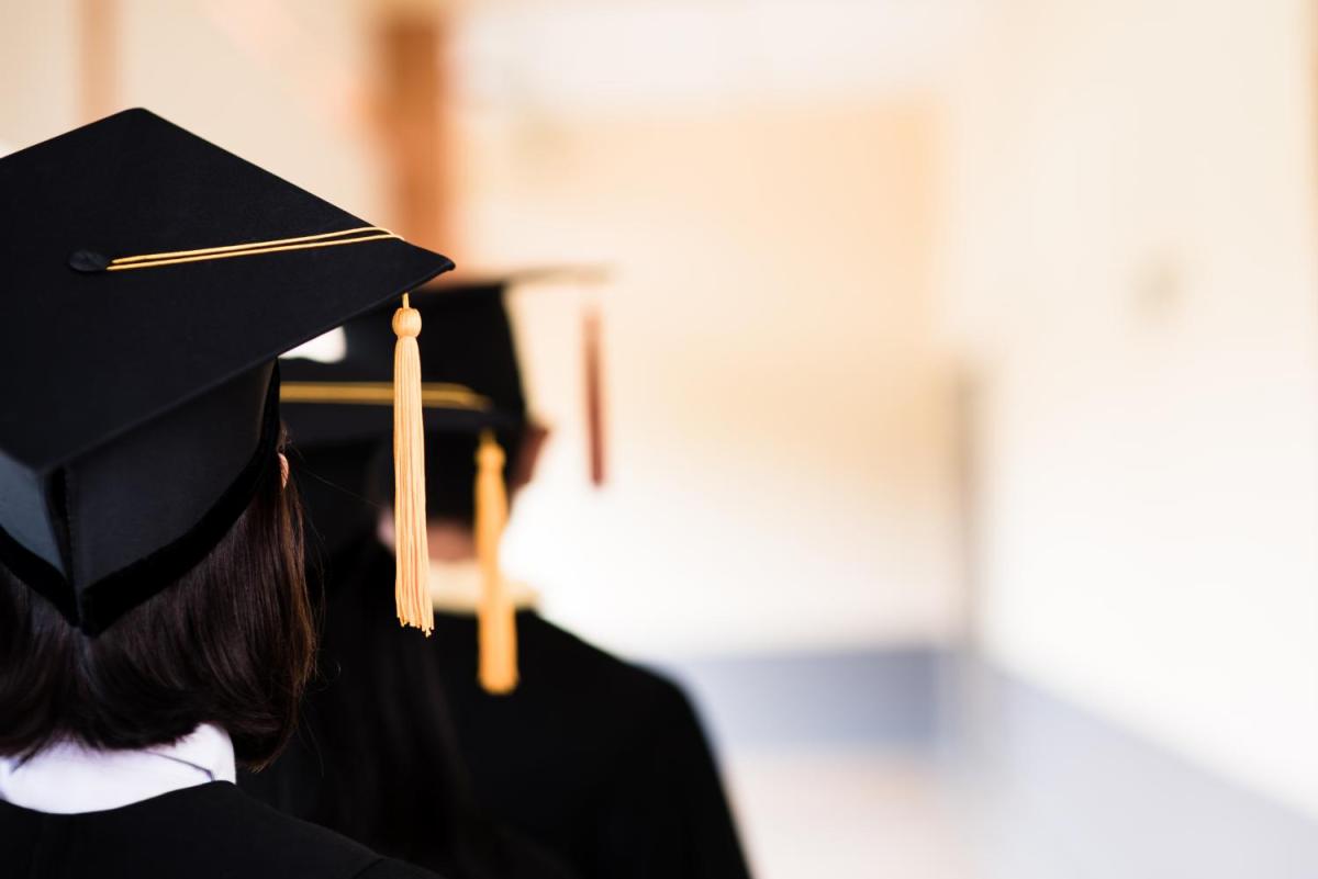 A couple of students wearing caps with their backs to the camera.